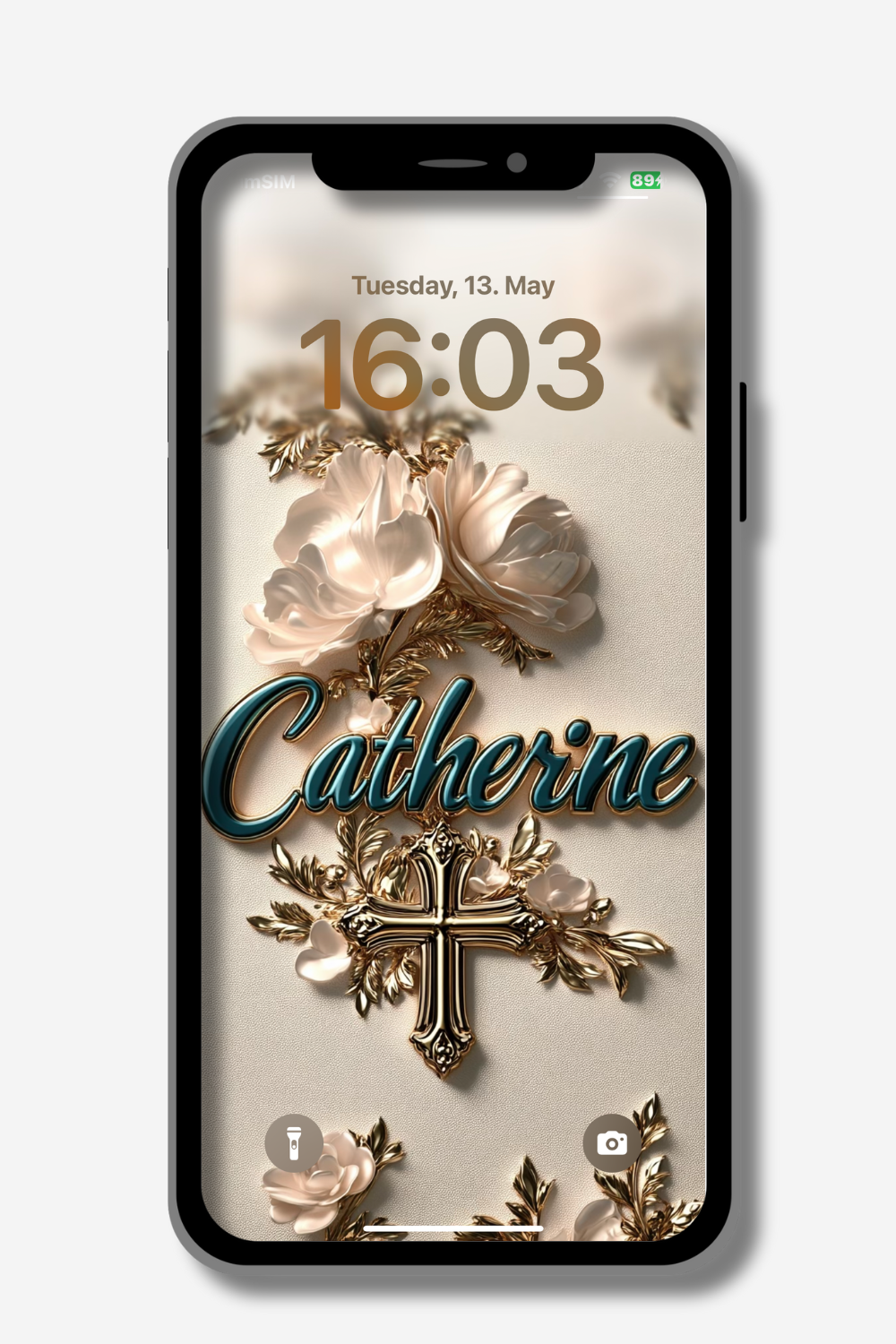 A smartphone displays a personalized lock screen wallpaper with the name "Catherine" in teal cursive, surrounded by ornate gold foliage and pale pink flowers. A golden cross is prominently featured. The date "Tuesday, 13. May" and the time "16:03" are visible at the top. Icons for flashlight and camera are at the bottom.