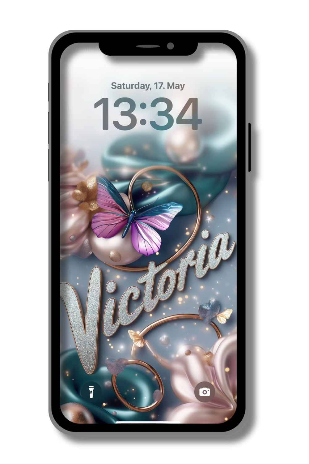 A smartphone screen displays a personalized lock screen. The date reads "Saturday, 17. May" and the time is "13:34". The wallpaper features a large, vibrant butterfly with pink and blue wings, surrounded by swirling teal and pink fabrics, gold rings, and smaller butterflies. The name "Victoria" is written in elegant, shimmering script across the center.